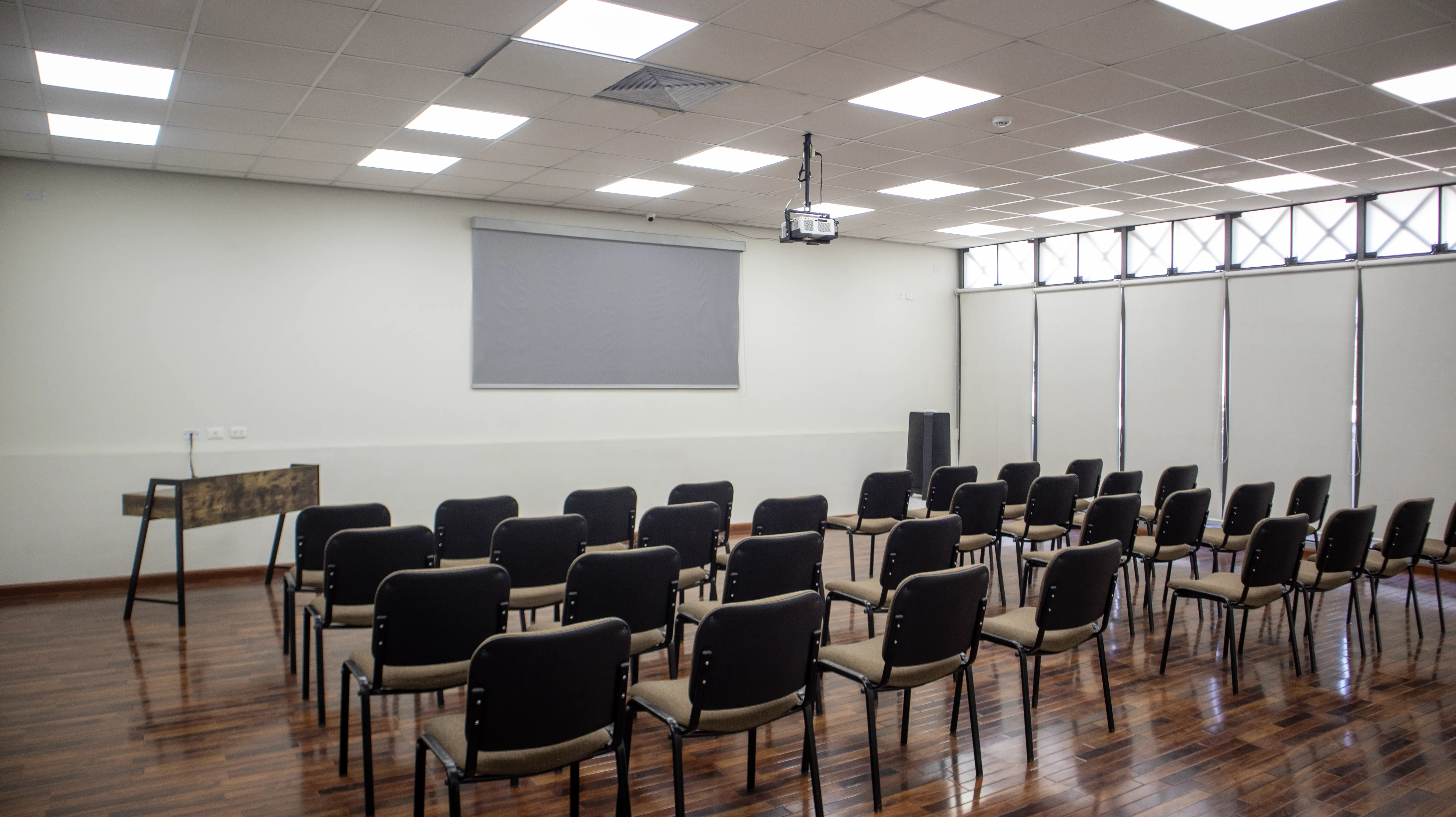 Sala de conferencias con sillas marrones mesa y proyector